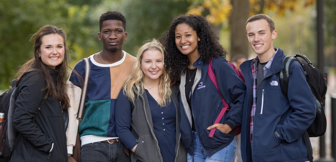 diverse group of five students smile at the camera