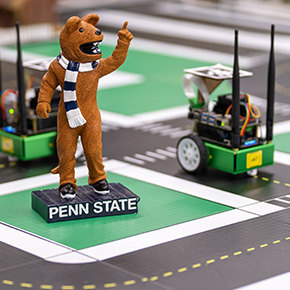 Nittany Lion decoration points in the air in front of a robotic car