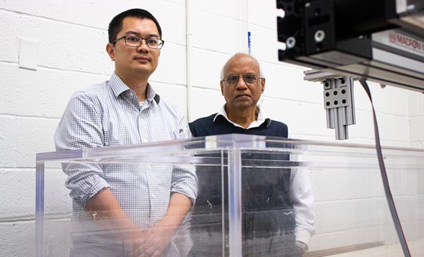 Two men stand in front of a tank of water in a research laboratory. 