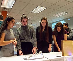 Four women look at objects on a table