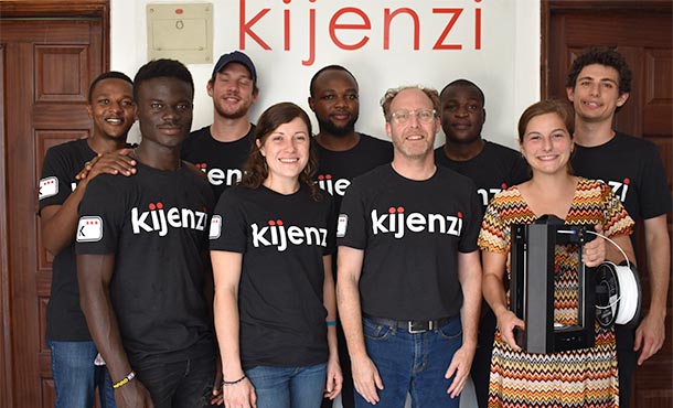 Nine people stand face forward while smiling.