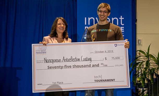 A man and a woman hold a large cardboard check made out to Nanoporous Antireflection Coatings for $75,000