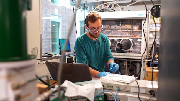 Bearded man wearing safety glasses in laboratory conducts an experiment in a laboratory.