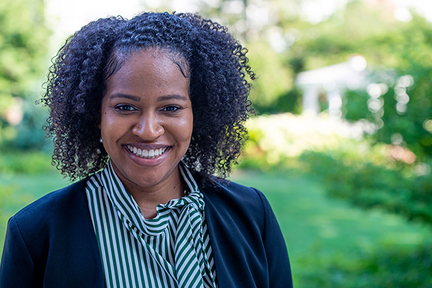 African American woman smiling with trees and bushes in the background