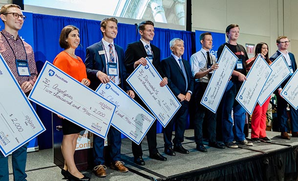 a line of students on a stage holding large presentation checks