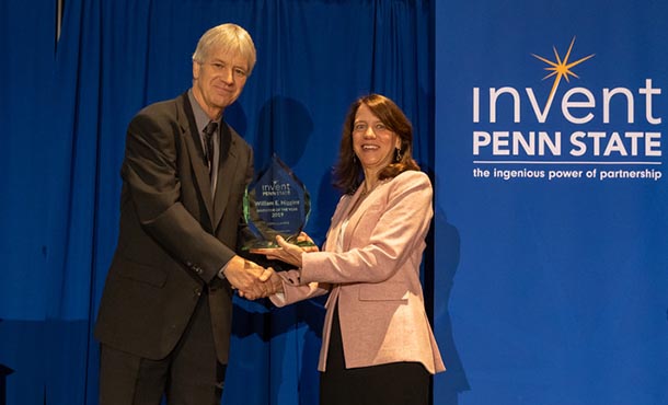 A man and woman shaking hands as he  accepts a trophy