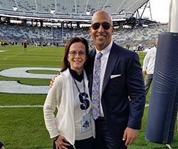 man and woman stand next to eachother on a football field