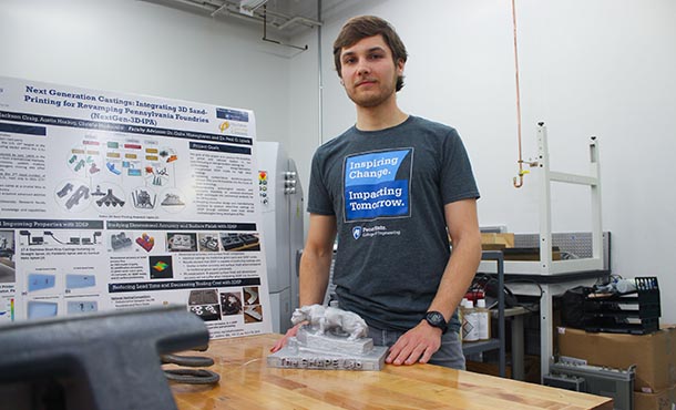 A man stands in an additive manufacturing lab with posters and equipment.