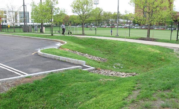 road with dry detention basin with some rock at the bottom