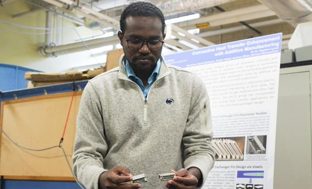 a man holds small piece of metal in a lab