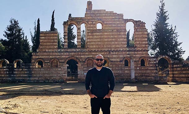 Joseph Najem stands in front of ruins.