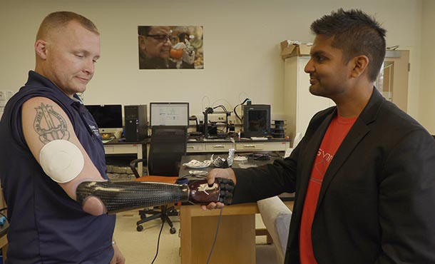 A man with a prosthetic right arm shakes hand with another man