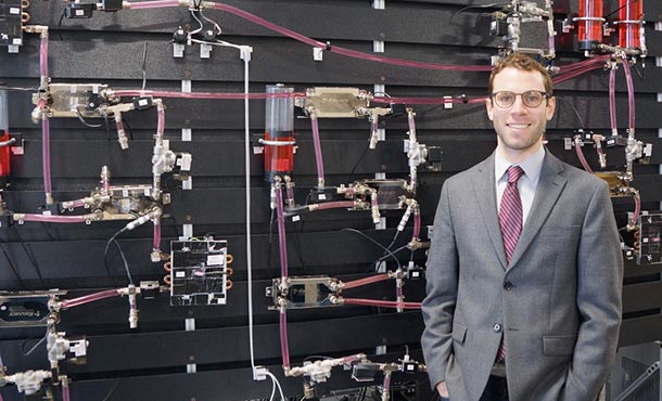 Herschel Pangborn standing in front of a wall of machinery.