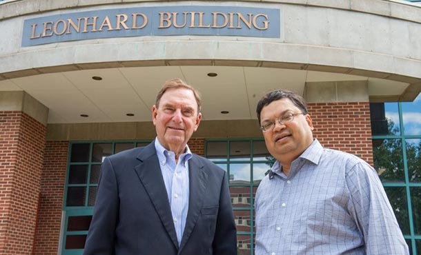 Two men in business attire stand before a building with a sign saying Leonhard Building.