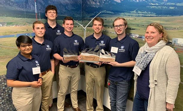 Seven people pose for a photo with trophies