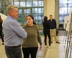 a man speaks to a woman about her research poster