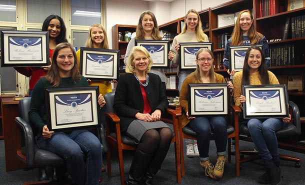 A group of undergraduate female students and a female administrator pose with certificates.