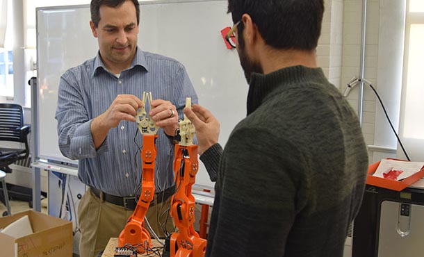 Alan Wagner, assistant professor of aerospace engineering, and graduate student Sagar Lakhmani adjust a pair of Braccio robotic arms on the latest generation of emergency evacuation robots in the Penn State Robot Ethics and Aerial Vehicles Lab.